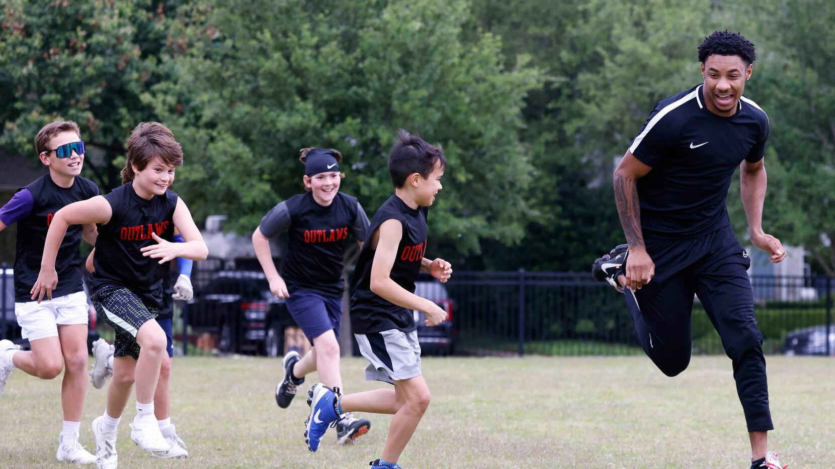 SMU’s Chris Megginson (right) runs past the kids during a special session of football drills...