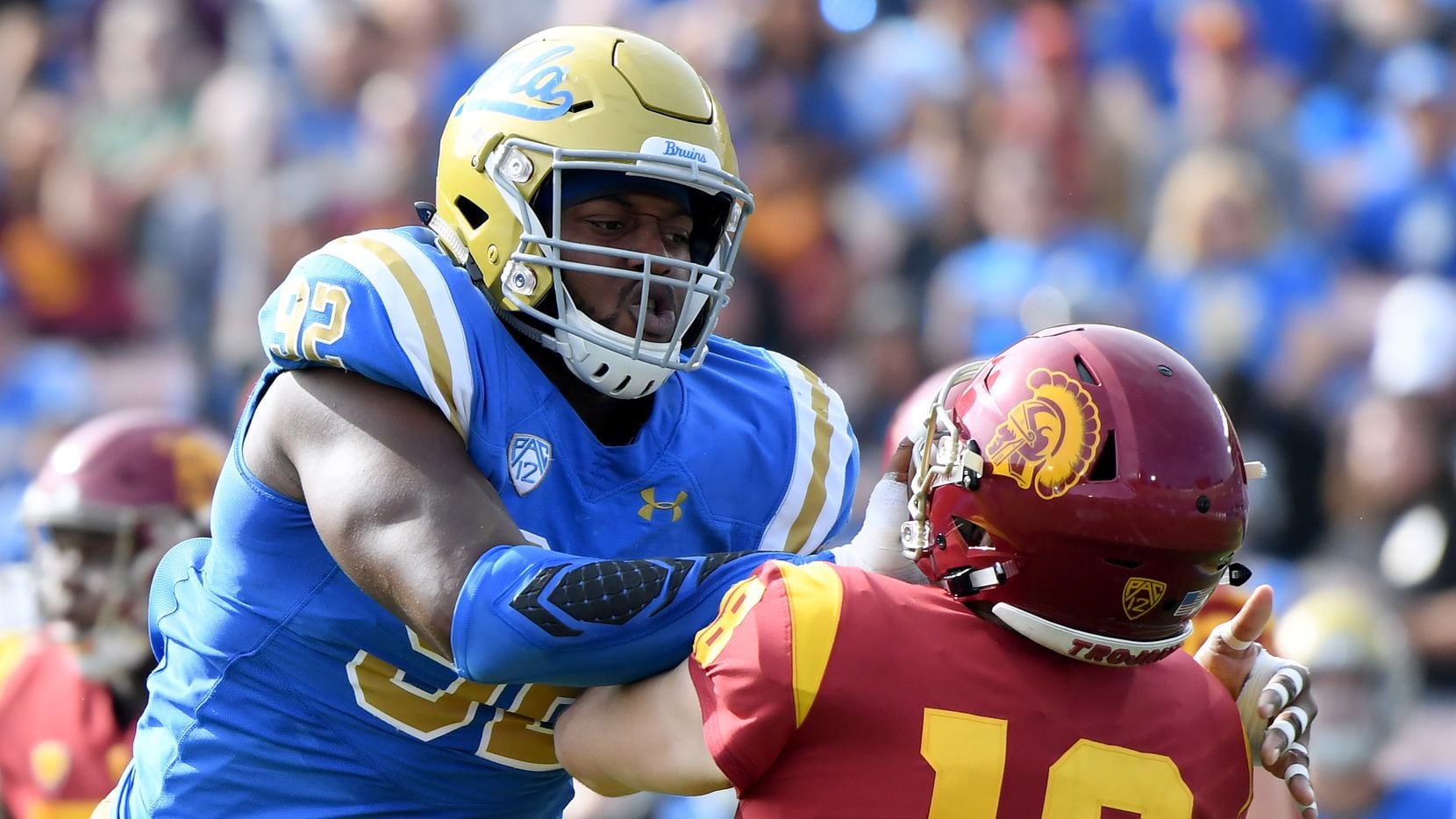 PASADENA, CALIFORNIA - NOVEMBER 17:   Osa Odighizuwa #92 of the UCLA Bruins gets his hands in the face of JT Daniels #18 of the USC Trojans during the first half at Rose Bowl on November 17, 2018 in Pasadena, California. (Photo by Harry How/Getty Images)