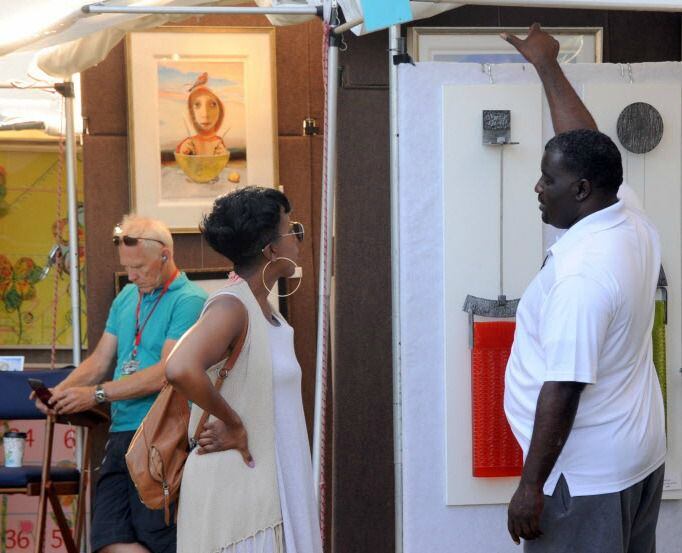Patrons browse an artists tent at a festival.