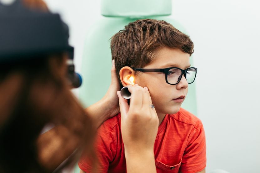 Un niño sujeto a un examen en su oído derecho.