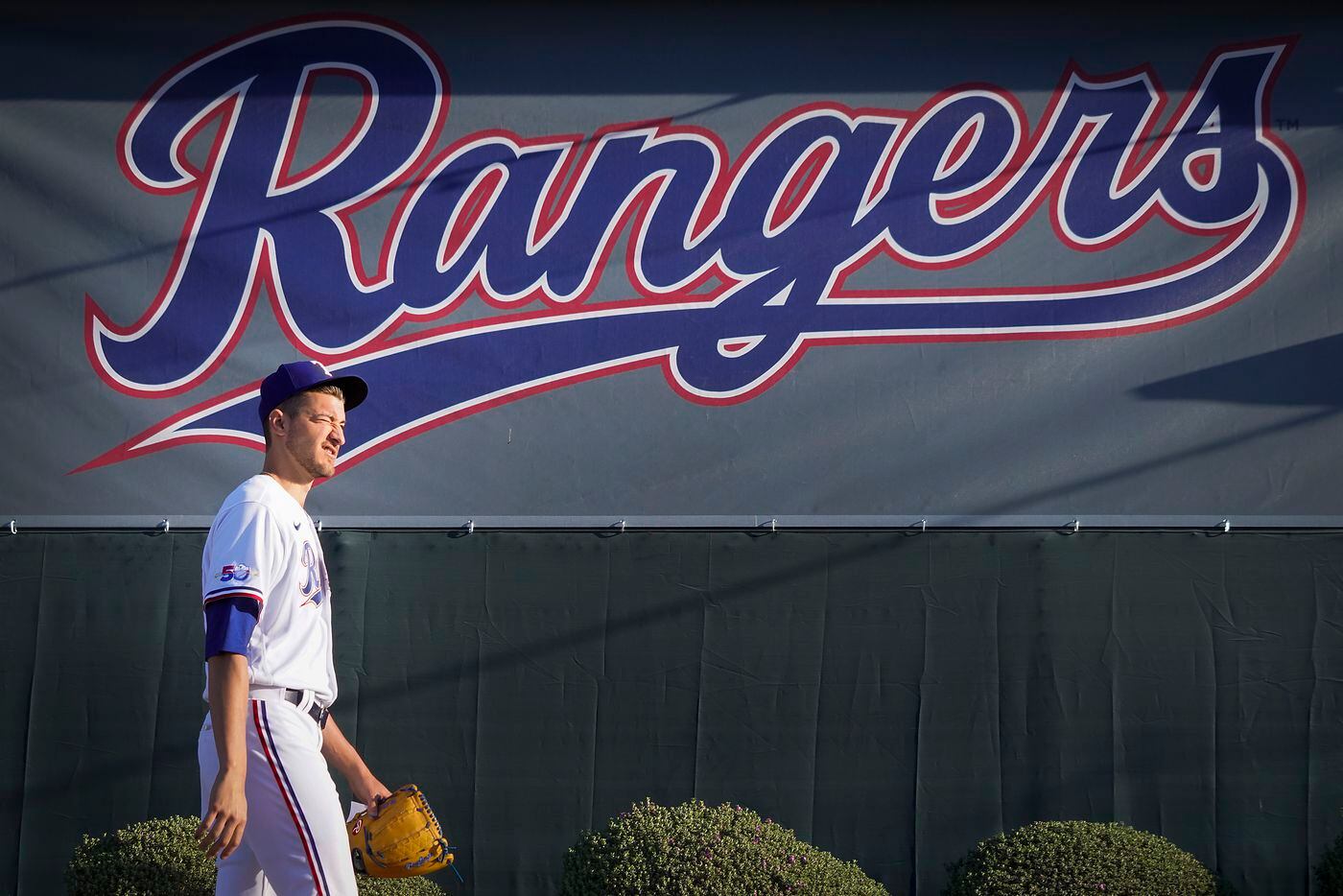 Texas Rangers pitcher Brett Martin squints against the rising sun as he walks to the...