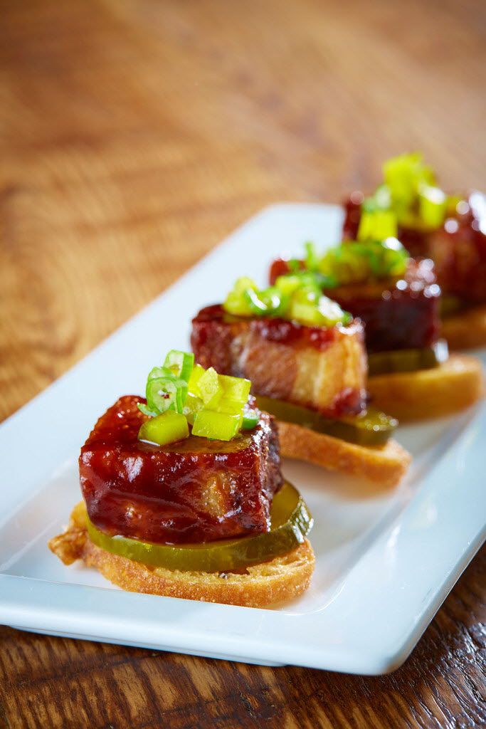 The Sugarbacon is an appetizer of pork belly and spicy pickles on a crostini.