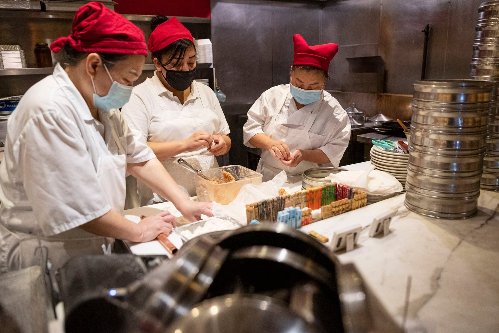 Dumpling makers Sophia Chen (left), Eliza Monica and Huajuan Shen  work with ingredients and...