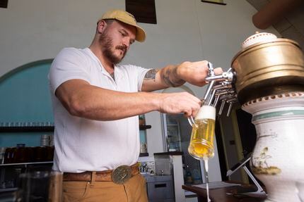 Jacob Boger pours Hart beer, one of the new beers created by Small Beer Works in the back....