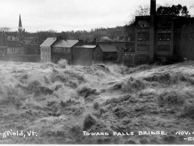In this photo provided by the Vermont Historical Society, floodwaters rage through...
