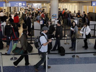 Travelers wait in line to go through security at Terminal D at DFW International Airport.