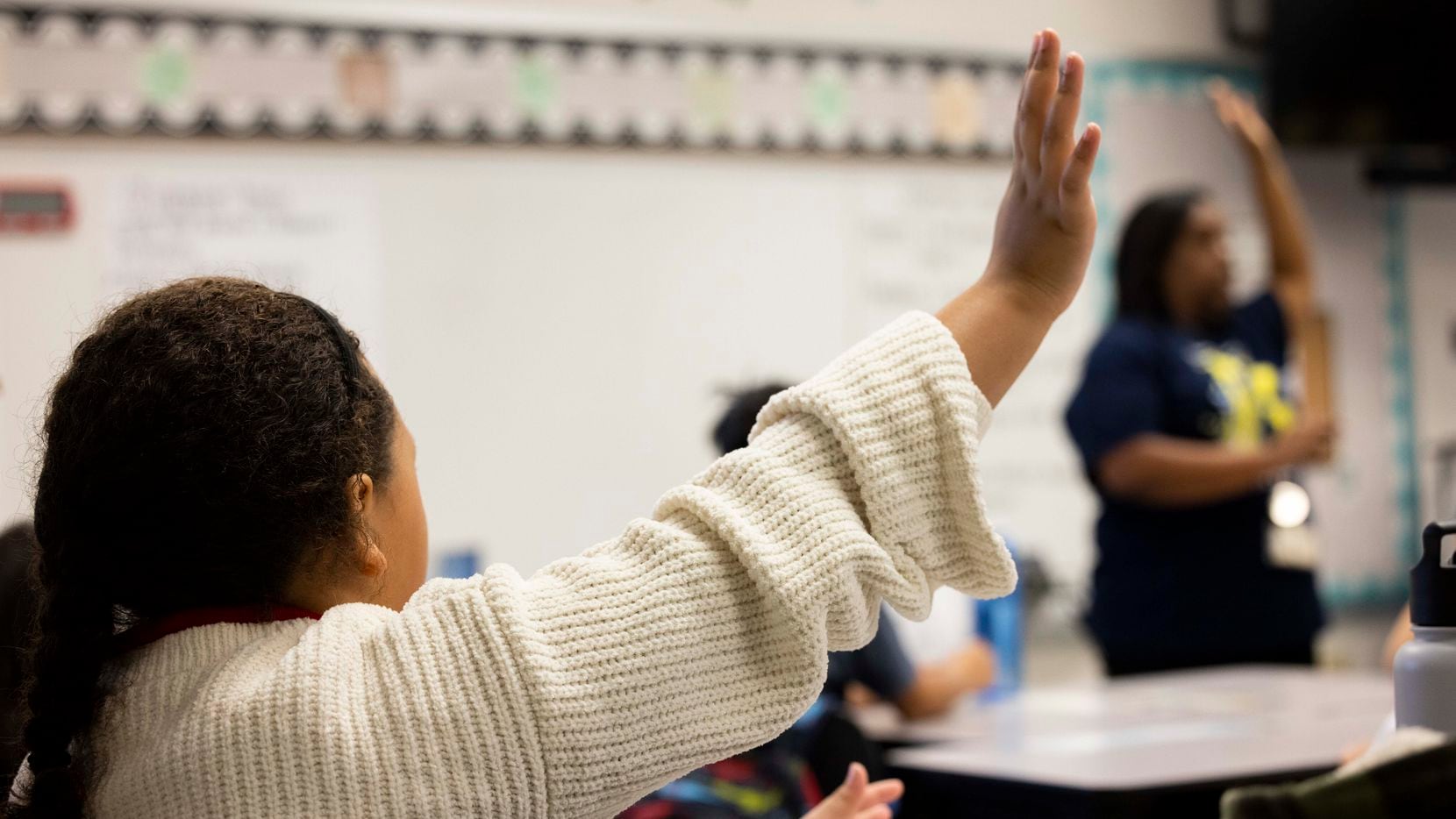 Students raise their hands as third-grade teacher Anjelica Turner teaches about character...