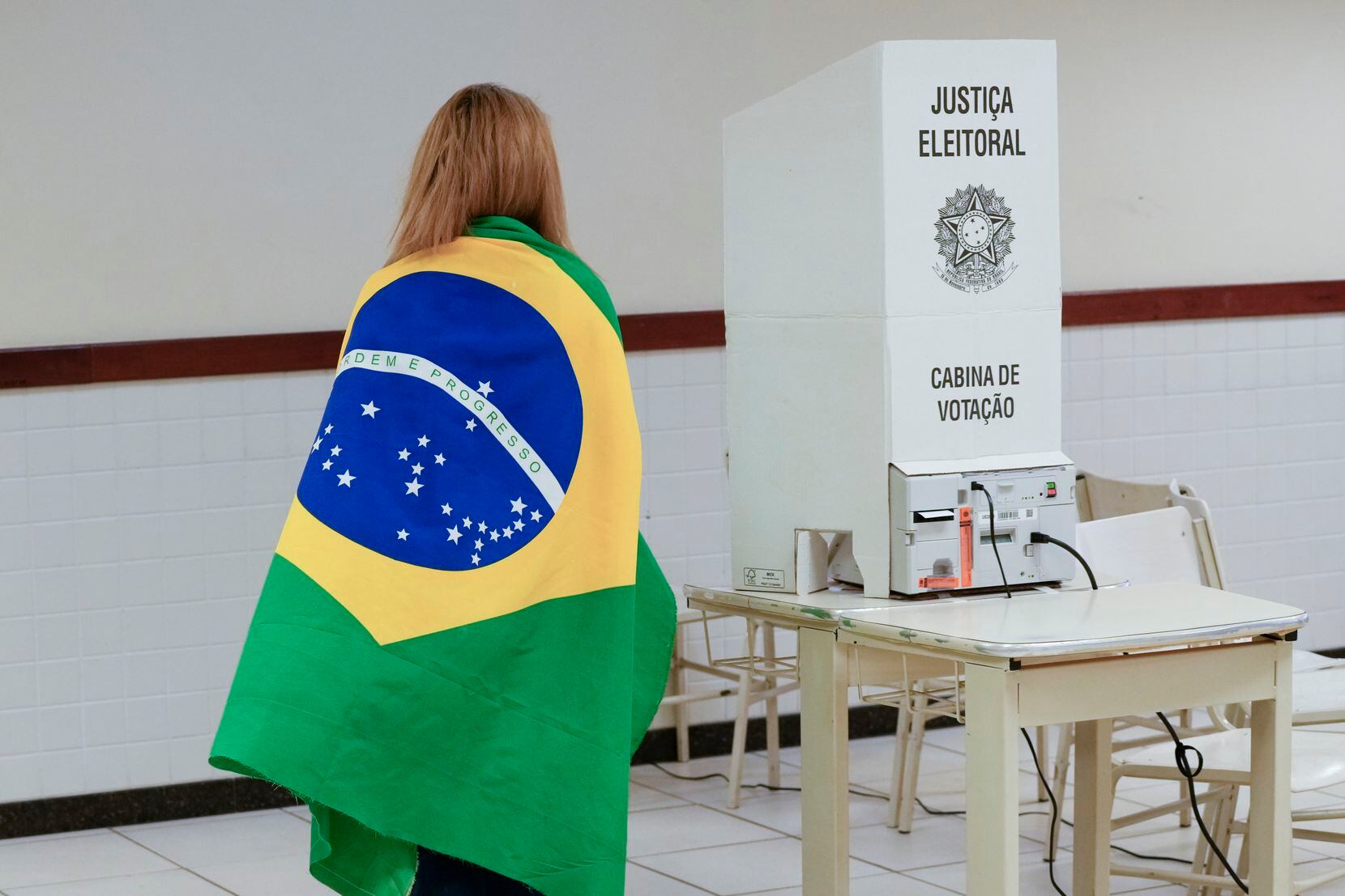 A voter wrapped in a Brazilian flag arrives to vote in a presidential a run-off pitting...