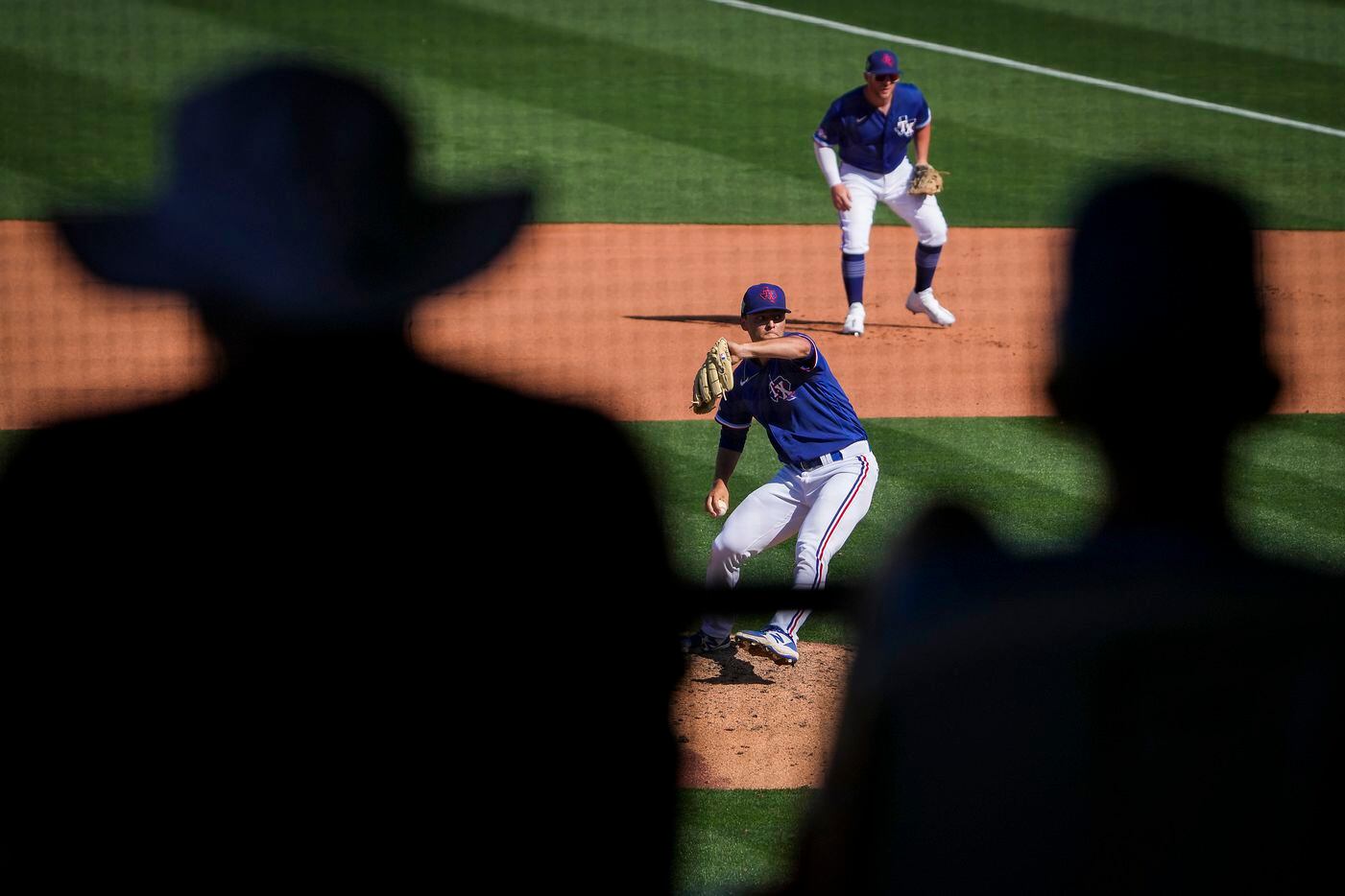 Texas Rangers pitcher Jack Leiter is seen through fans in the stands as he delivers during...