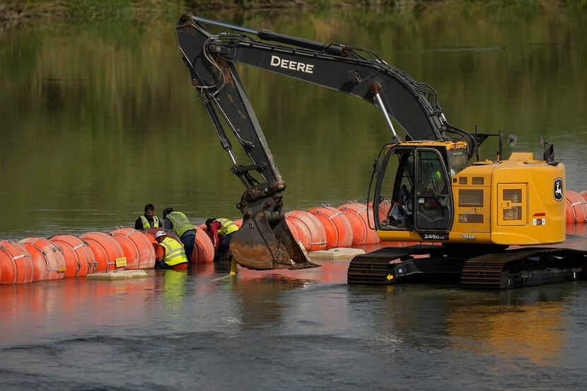 Workers made adjustments to buoys being used as a barrier along the Rio Grande, Monday, Aug....