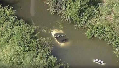 A car lies submerged in a creek Tuesday morning near Interstate 635 and Freeport Parkway in...