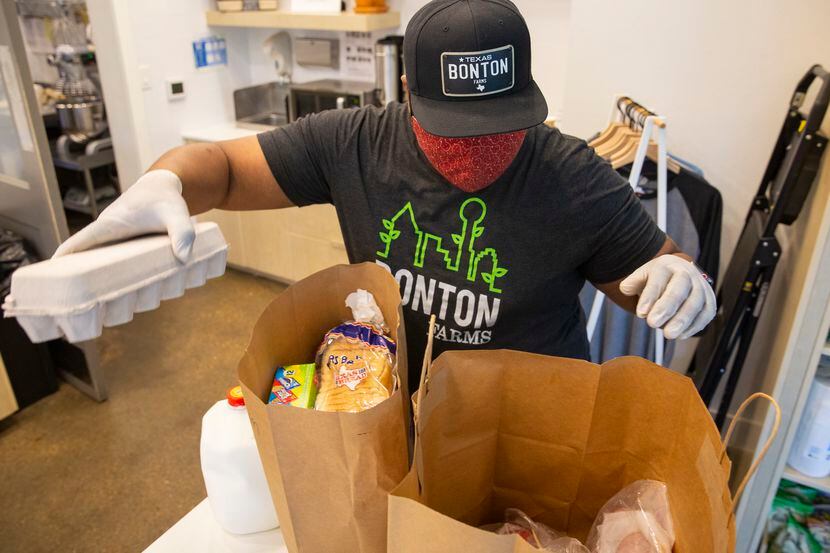 Clifton Reese, administrador en The Market at Boston Farms, prepara bolsas con alimentos...