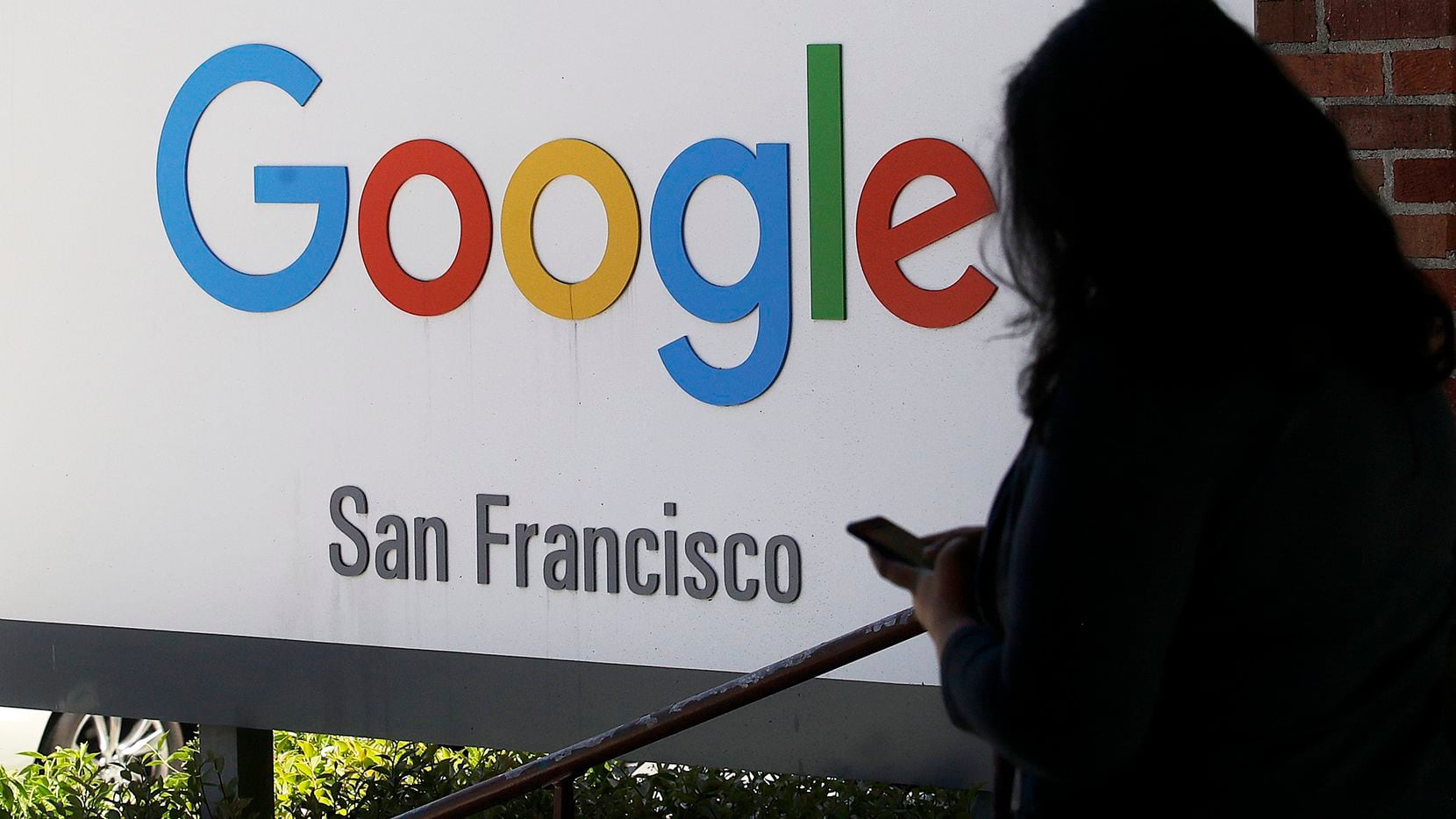 Una persona camina frente a la entrada de las oficinas de Google en San Francisco.