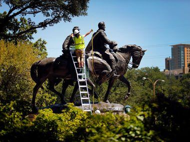 A crewman from Howell Crane and Rigging, Inc measures the height of the Robert E. Lee statue...