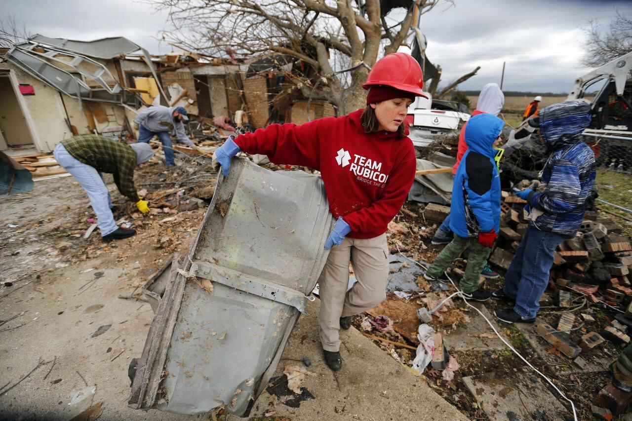 Team Rubicon volunteer Molly Gayden of Fort Worth hauls a piece of garage door to the curb as they clean up the tornado ravaged home on Mesa Wood Drive in Glenn Heights.