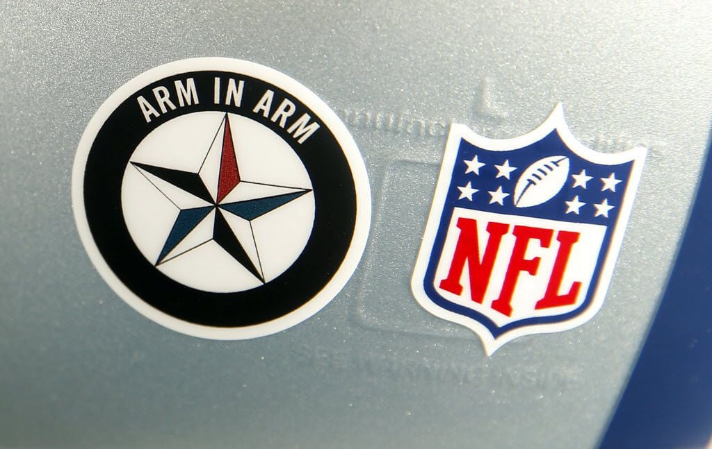 The Dallas Cowboys players are wearing a special Arm-in-Arm decal on their helmets during...