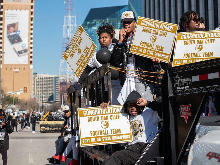 Members of the South Oak Cliff High School football team ride on a trailer with signs and their UIL medals during Saturday's parade.