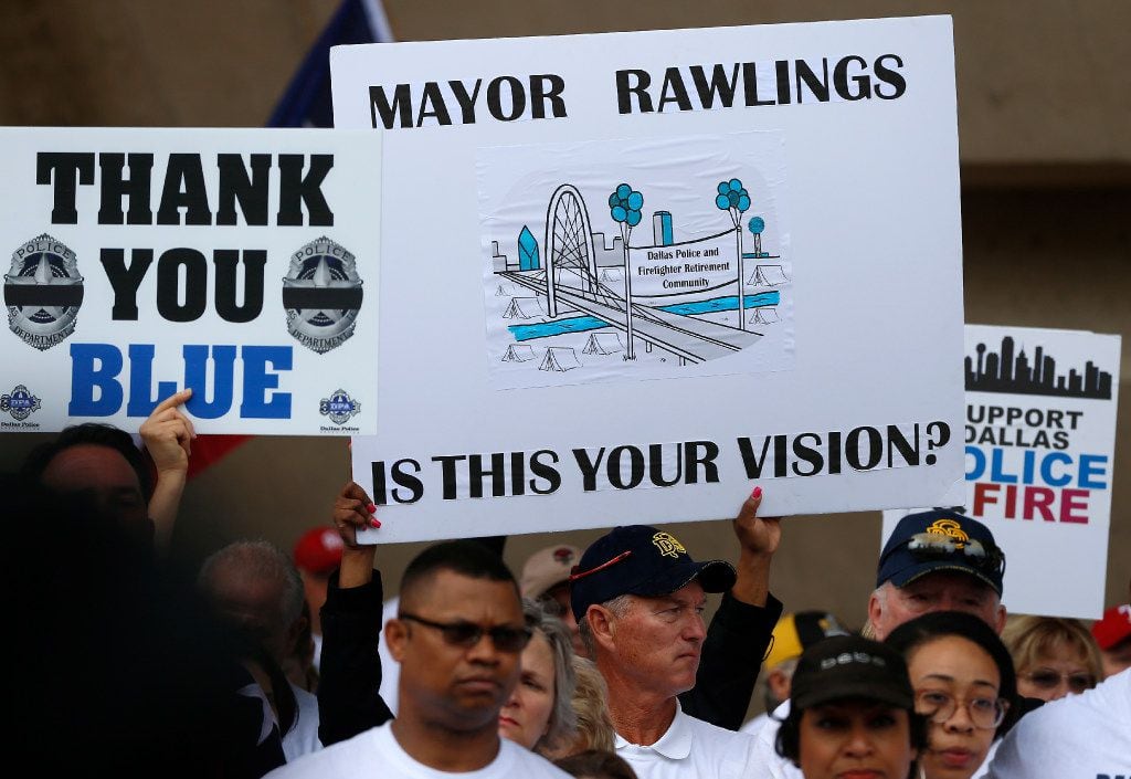 Dallas police and fire retirees hold signs during a rally against Mayor Mike Rawlings at City Hall on April 26, 2017.