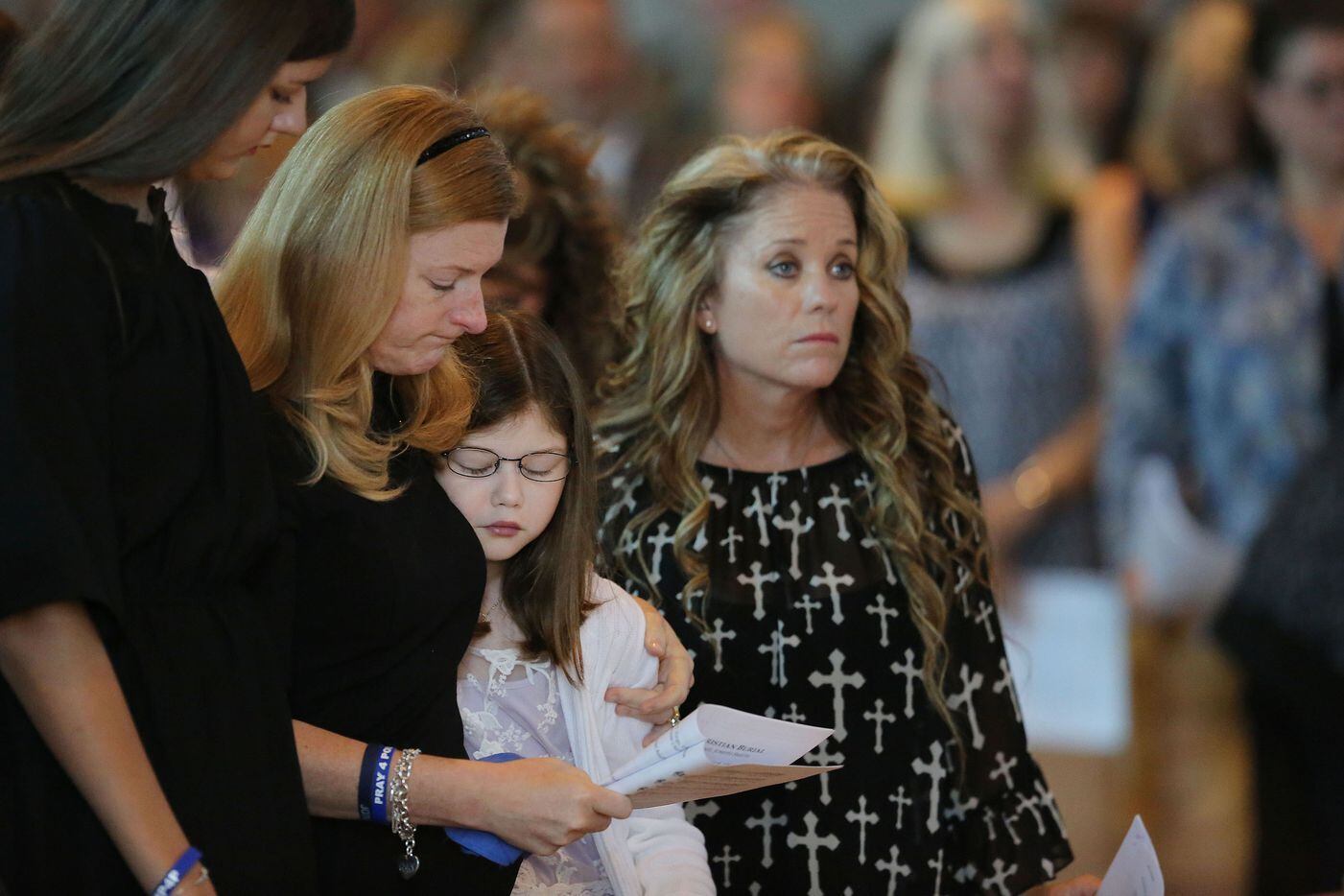 Heidi Smith (second to left) stands between her daughters, Victoria (left) and Caroline Smith (center), with Dallas Sr. Cpl. Marcie St. John (right) standing nearby during the funeral for her husband, Dallas police sergeant Michael Smith.