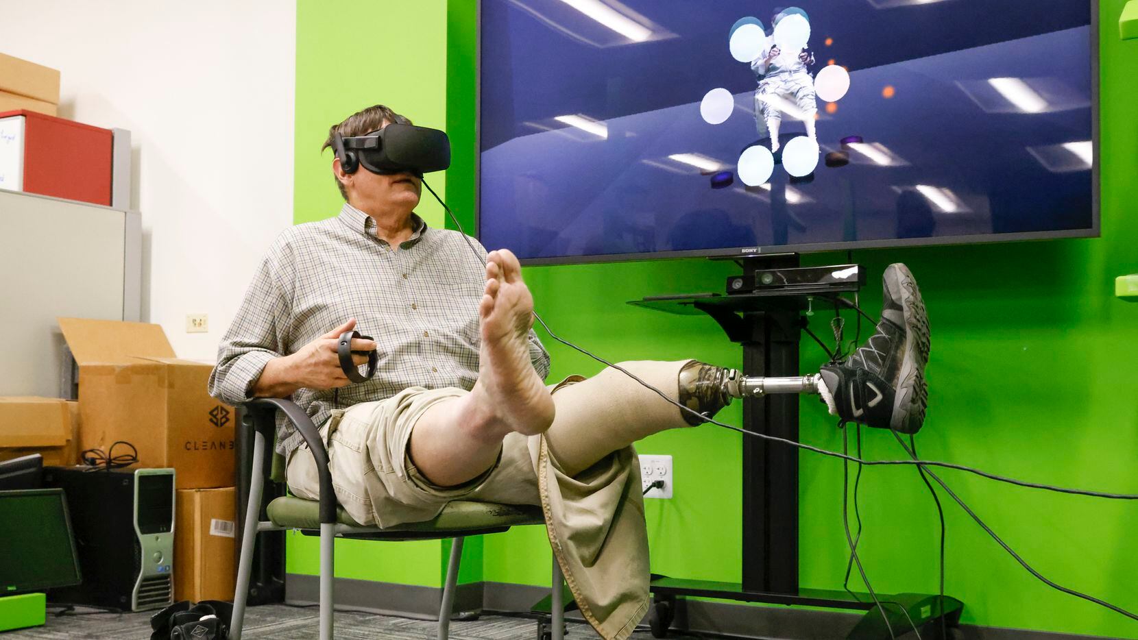 Navy veteran Frederick Dean Peterson, wearing a VR headset, lifts up his legs as he...