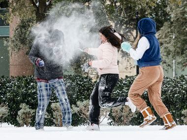 Erik Lara, left, reacts to a snowball dump from Alyssa Gonzalez, center, and Merlyn Montoya...
