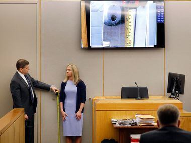 Defense attorney Toby Shook measures the height of a keyhole beside Amber Guyger during...