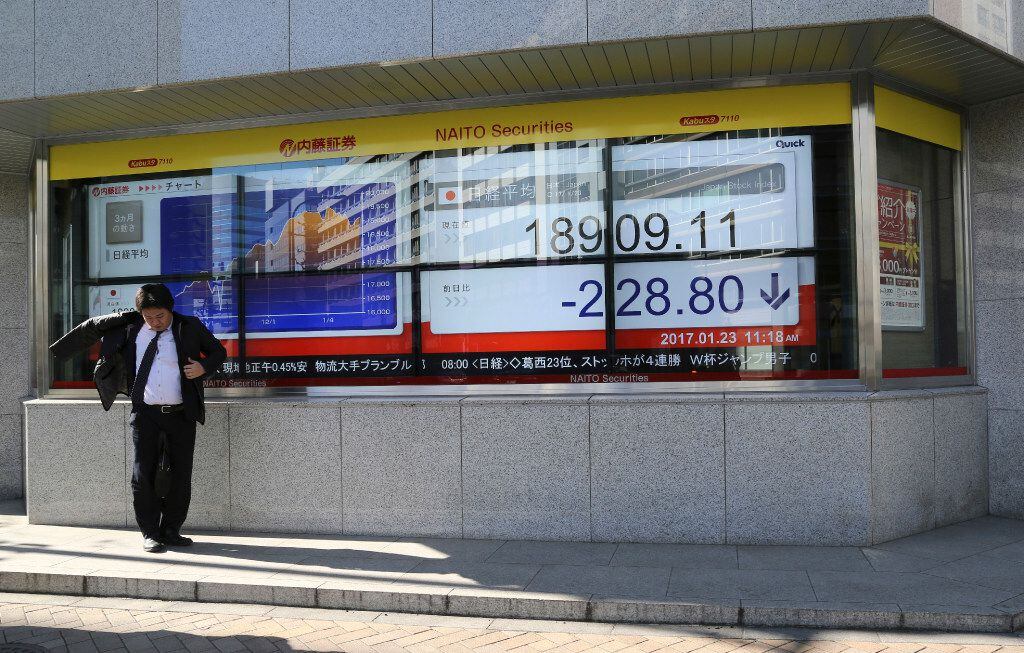 A man stands by an electronic stock board of a securities firm in Tokyo, Monday, Jan. 23,...