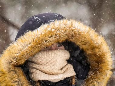 Roxie Hunter bundles up against the cold as snow falls in Prairie Creek Park as a winter...