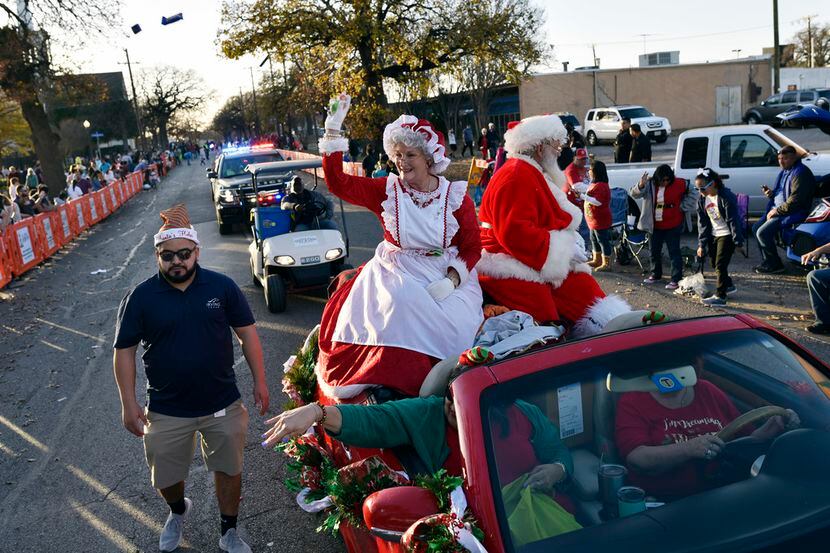 Mrs. Claus and Santa Claus wave to families while tossing candy during the Irving Holiday...