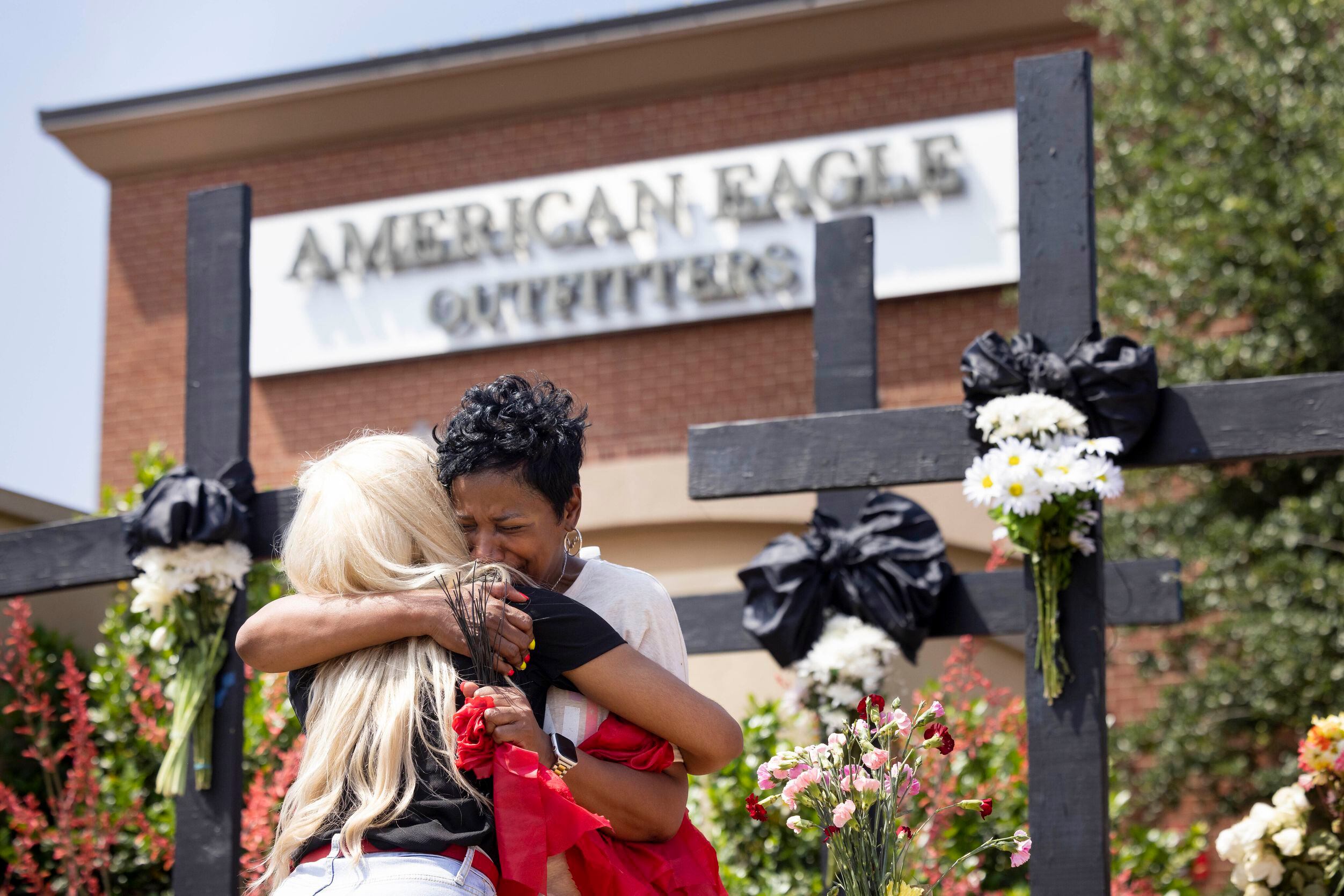Cheryl Jackson shares an embrace at a memorial outside the mall after a mass shooting at...