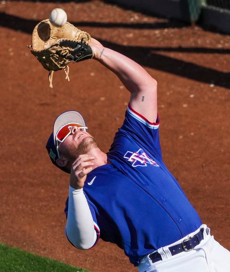 Texas Rangers infielder Blaine Crim makes a catch in foul territory during the eighth inning...
