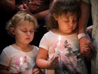 Makenzie and Morgan Miller attend a vigil with their grandfather, outside the emergency room...