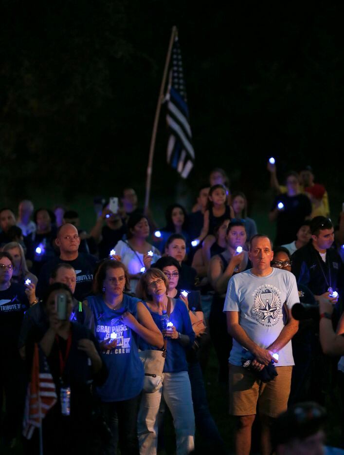 People hold blue lights during the Tribute 7/7 closing ceremony at Dallas Police Memorial in...