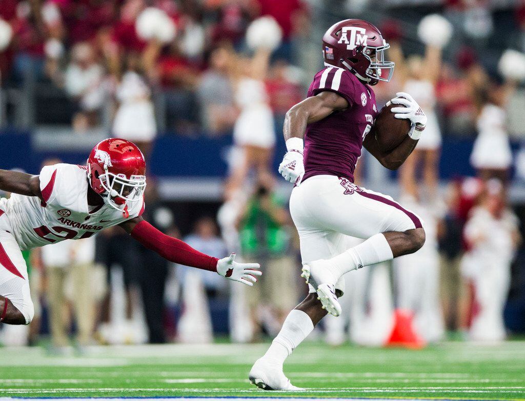 FILE - Texas A&M Aggies running back Jashaun Corbin (7) escapes a tackle by Arkansas Razorbacks defensive back Montaric Brown (21) while running a punt back for a touchdown during the first quarter of an NCAA football game between Texas A&M and Arkansas on Saturday, September 29, 2018 at AT&T Stadium in Arlington, Texas. (Ashley Landis/The Dallas Morning News)