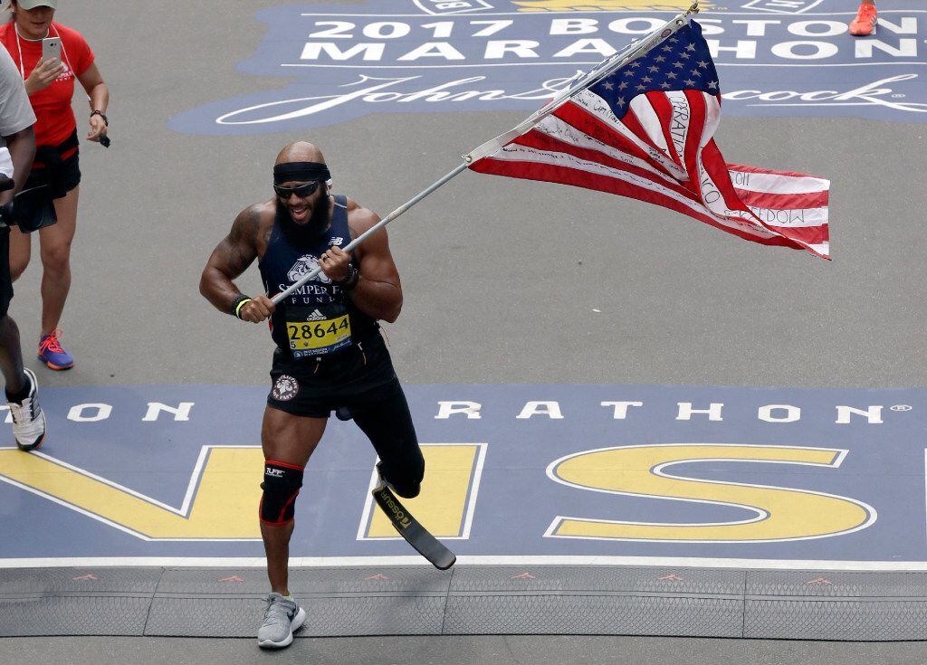Jose Sanchez, of San Antonio, carries the United States flag across the finish line in the...