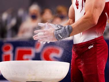 University of Oklahoma's Allan Bower chalks his hands before performing on the pommel horse...