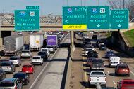 Semi-trucks drive slowly in traffic along Interstate 30 near the exit for Interstate 45 and...