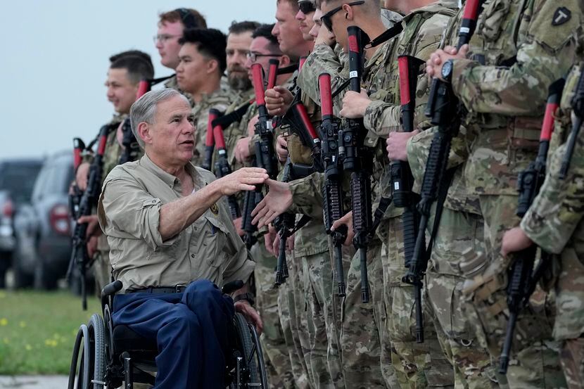 Texas Gov. Greg Abbott shakes hands with members of the Texas National Guard as they prepare...