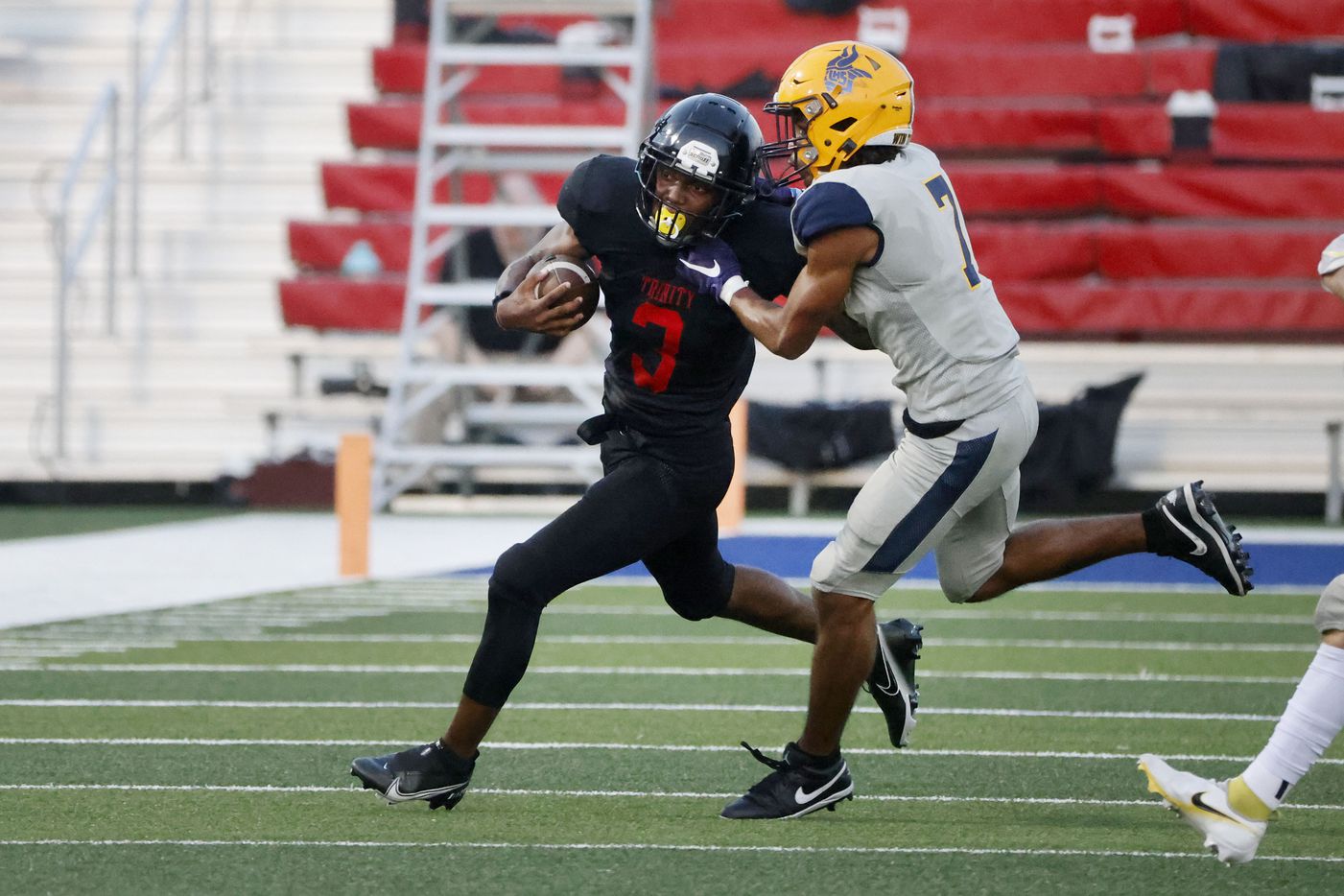Euless Trinity running back Garry Maddox (3) tries to get out the grasp of Arlington Lamar...