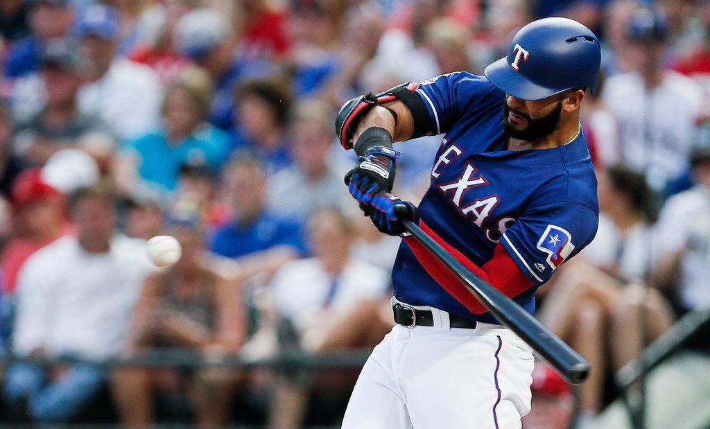 Texas Rangers' Nomar Mazara makes contact for a sacrifice fly during the third inning of a baseball game against the Houston Astros, Saturday, July 13, 2019, in Arlington, Texas. Shin-Soo Choo and Danny Santana scored on a throwing error by Astros center fielder George Springer. (AP Photo/Brandon Wade)