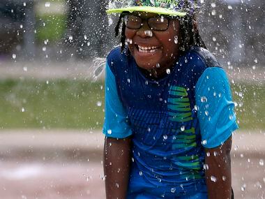 Elijah Darby, 6 reacts as water comes down on his head at Frisco Commons Spray Park in...