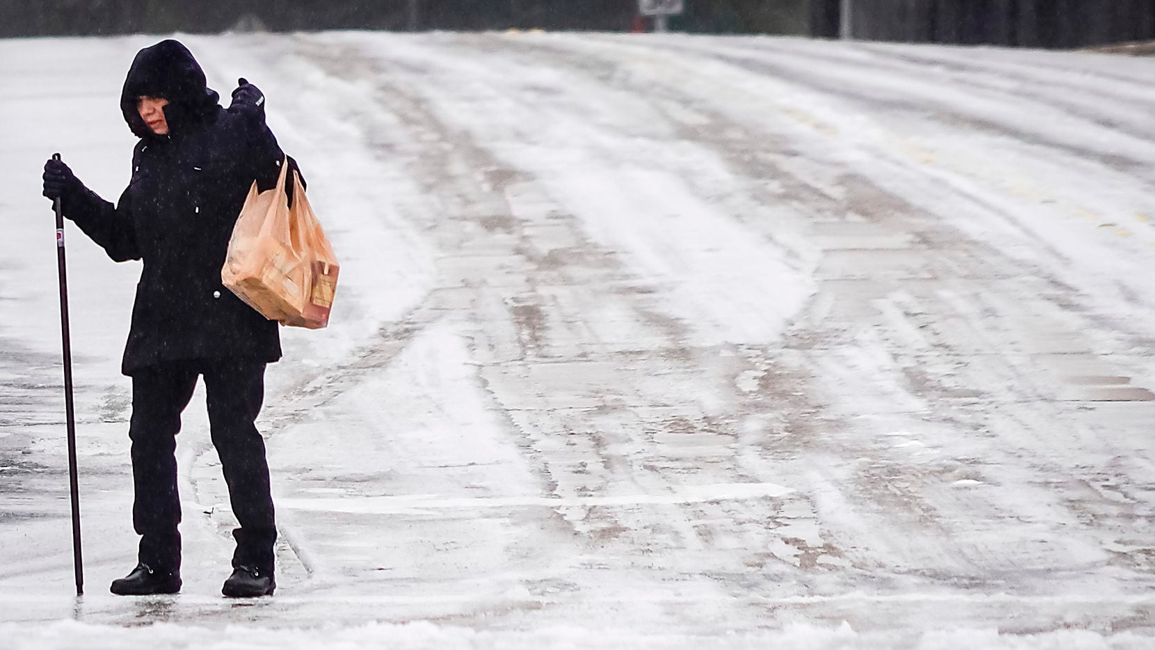 A woman carries bags of groceries while walking along Custer Parkway near Renner Road on...