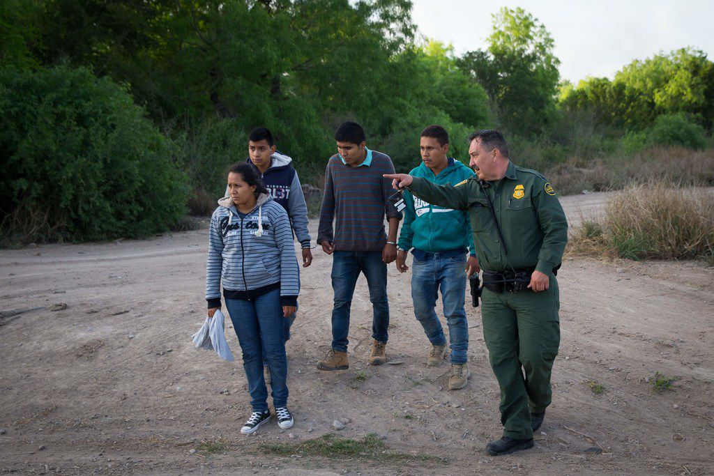 A Border Patrol agent apprehends immigrants shortly after they crossed the border from...