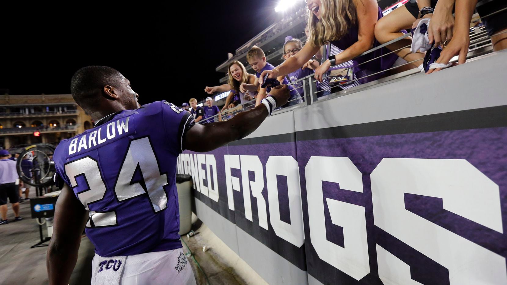 TCU running back Darwin Barlow (24) gives away his gloves to a fan after a win over...