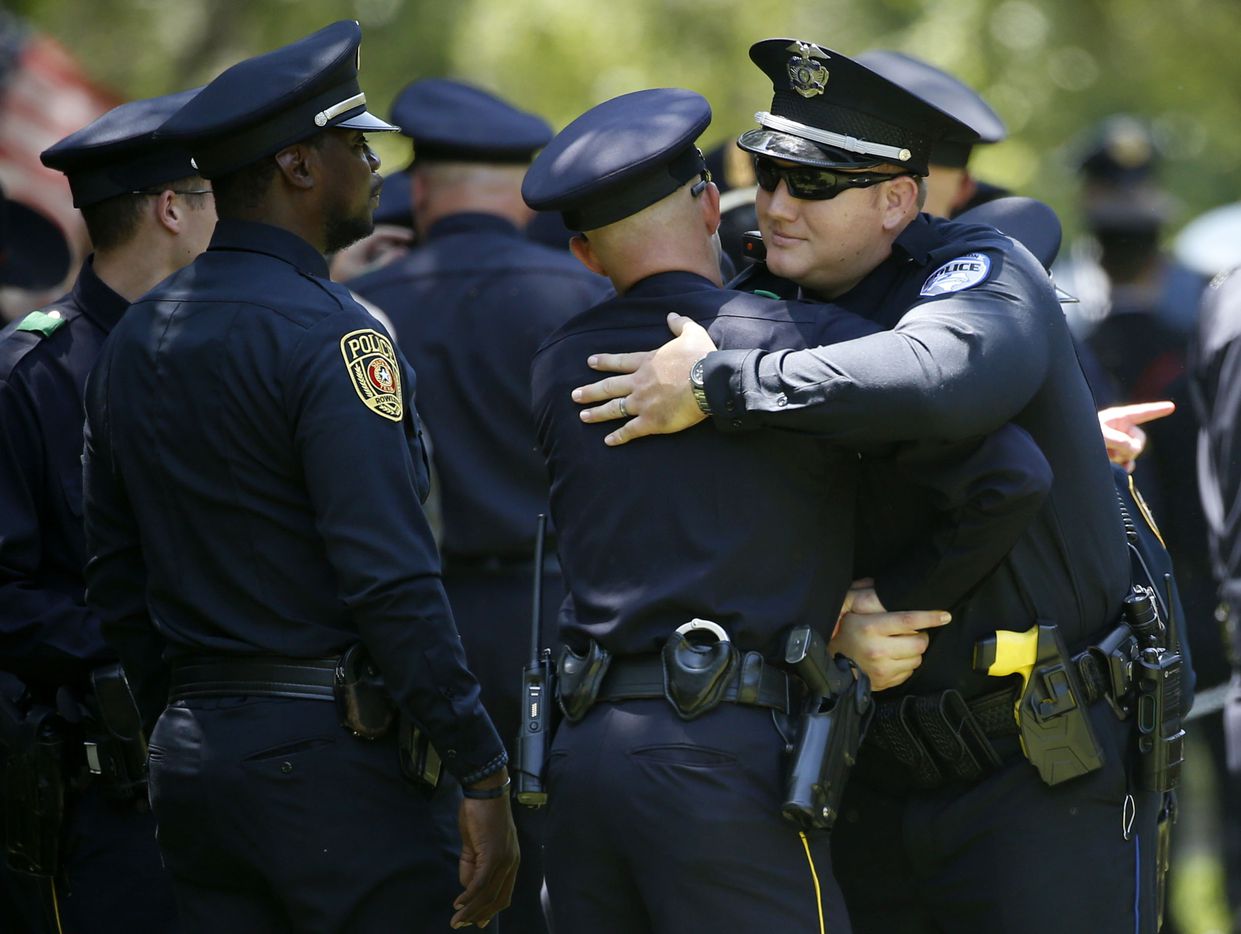 A Richardson police officer (right) hugs another police officer at the burial for fallen...