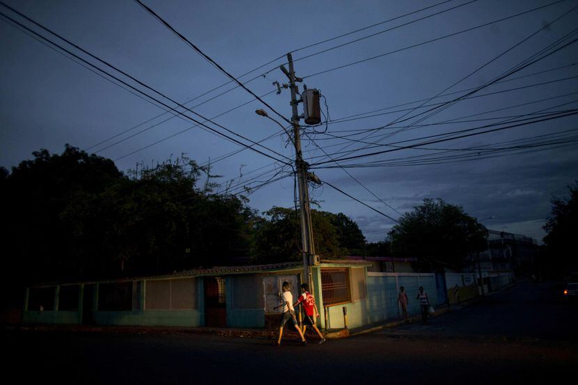 Residente de la vecindad de La Chinita, en Maracaibo, caminan en una noche oscura por la...