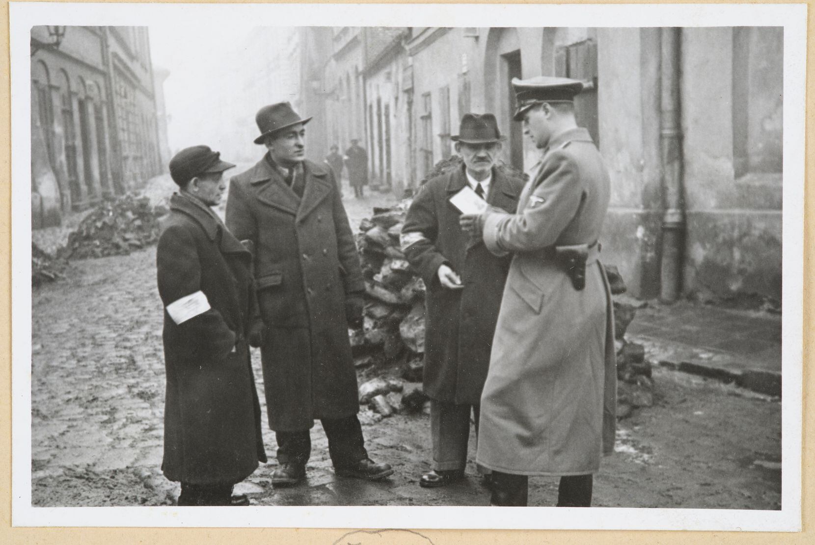 A German policeman checks the identification of Jewish people in the Krakow ghetto during...