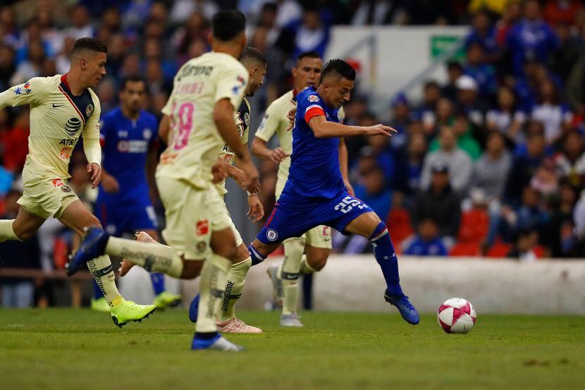 Roberto Alvarado (derecha) de Cruz Azul se desmarca con el balón frente a jugadores del...
