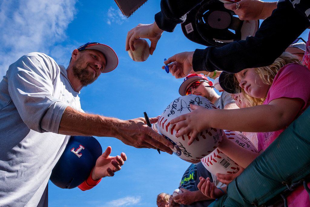 Texas Rangers outfielder Hunter Pence signs autographs before a spring training baseball...