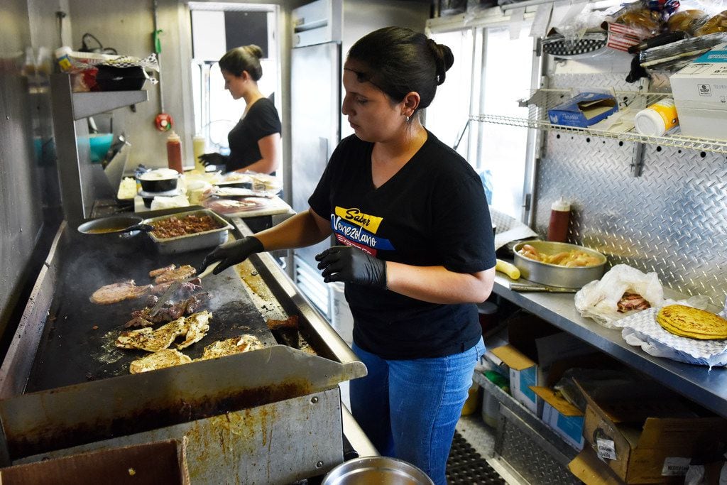 Co-owner Dariela Cuadrado, of Sabor Venezolano Express, cooks meat inside her food truck...